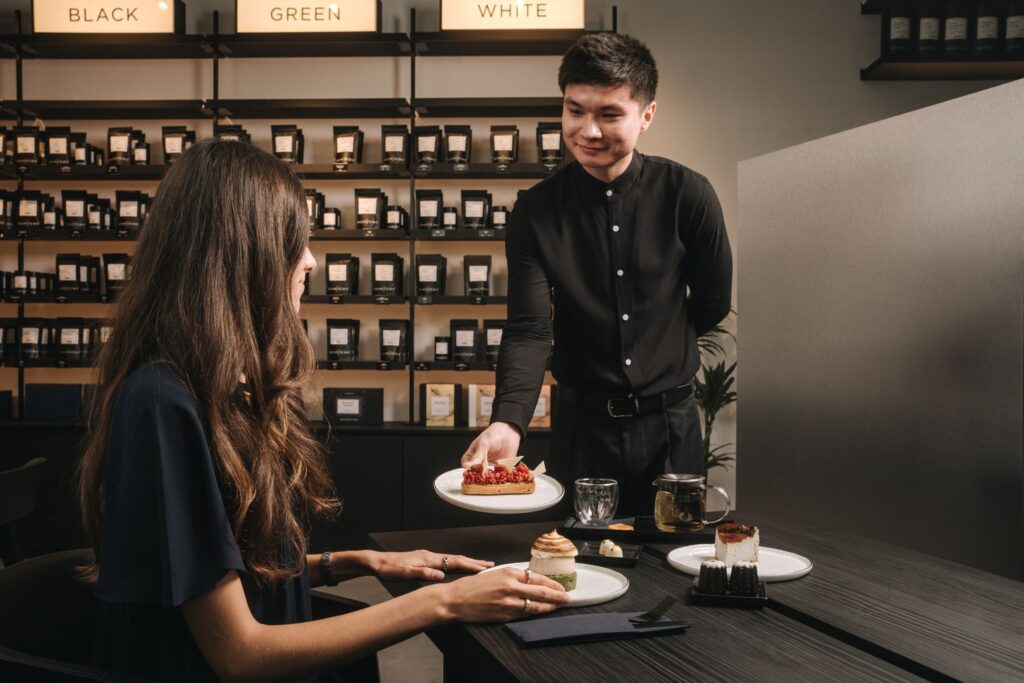 Waiter serving tea infused dessert to customer